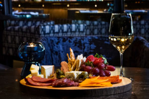 A table set for dinner with a variety of dishes, including a charcuterie board, salad, and cocktails.