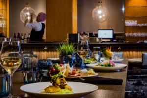 A table set for dinner with a variety of dishes, including a charcuterie board, salad, and cocktails.