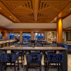 A modern restaurant with a bar, tables, and chairs.