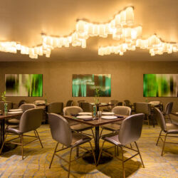 A modern restaurant with a bar, tables, and chairs.