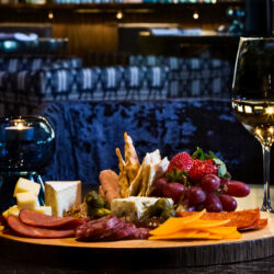 A table set for dinner with a variety of dishes, including a charcuterie board, salad, and cocktails.