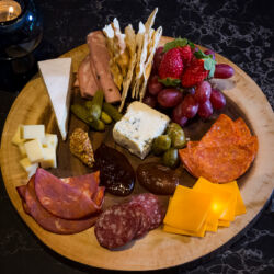 A table set for dinner with a variety of dishes, including a charcuterie board, salad, and cocktails.