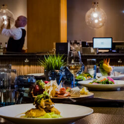 A table set for dinner with a variety of dishes, including a charcuterie board, salad, and cocktails.